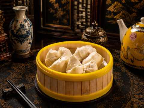 Steamed barbecue pork buns in a yellow-rimmed bamboo steamer