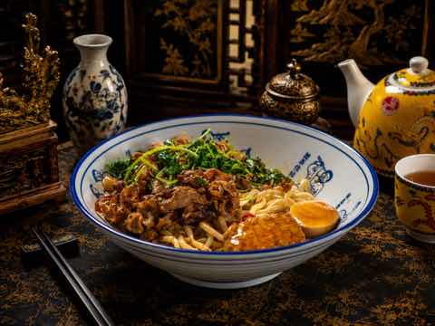 Noodle bowl with beef, leafy greens and a halved egg