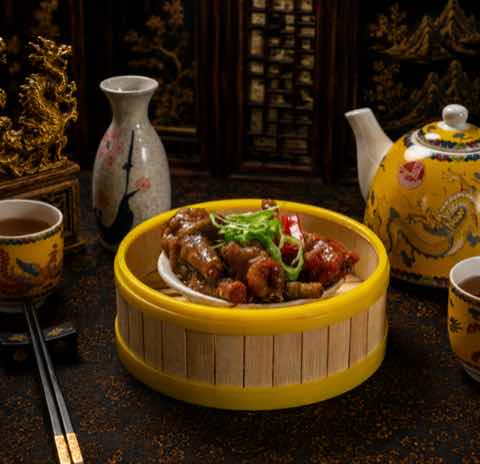 Braised chicken feet in a dark sauce topped with spring onion