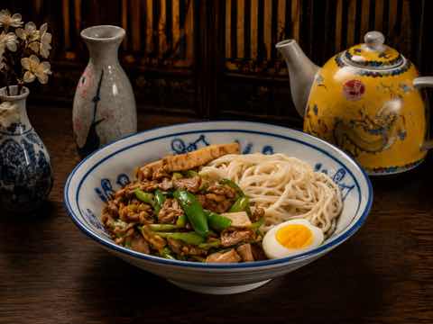 Braised pork noodle bowl with a halved soft egg and greens