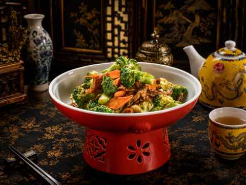 Broccoli and carrot stir-fry served in a red pedestal bowl
