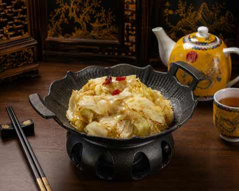 Braised cabbage with red chili in a dark cast iron pot