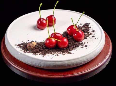 Fresh cherries with dark crumb arranged on a white plate