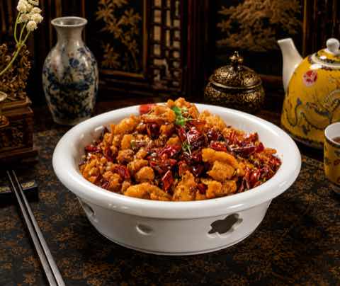 Sichuan chili chicken heaped with dried red chilies in a white bowl