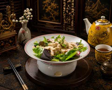 Chilled salad greens dressed and served in a rimmed porcelain bowl