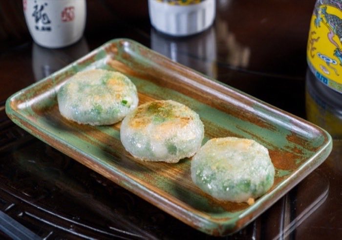 Pan-fried chive cakes on a green glazed plate