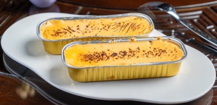 Two torched custard desserts served in gold foil cases