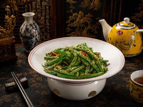 Dry-fried green beans with a minced garnish in a white bowl