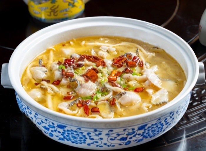Fish fillets in a clear peppery broth served in a blue and white pot