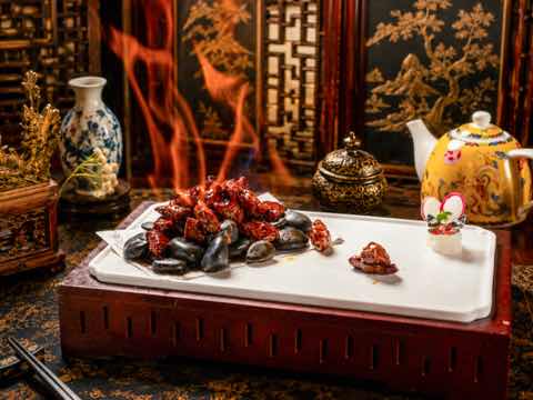 Beef cubes served on hot stones with flames rising behind the plate