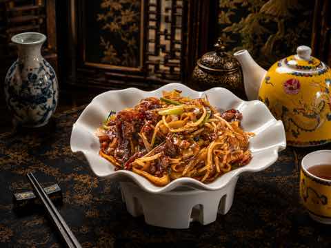 Fried rice noodles with beef and bean sprouts in a scalloped bowl