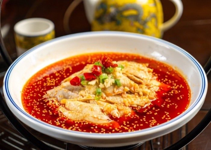 Fillets of white fish resting in bright red chili oil