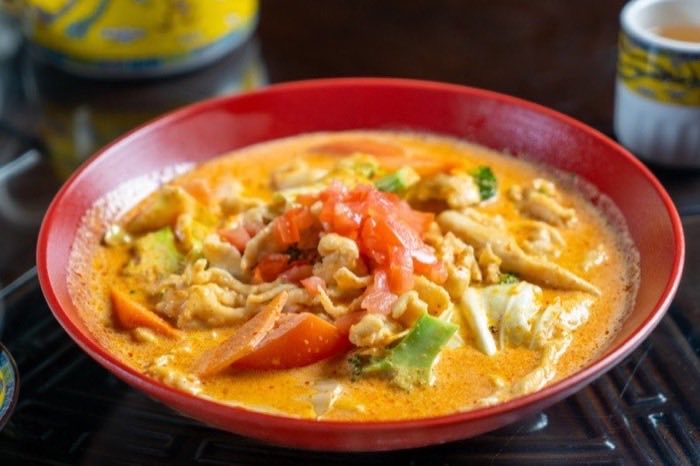 A creamy seafood and tomato soup in a red lacquer bowl