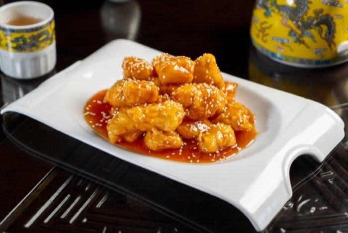 Sesame-coated chicken pieces in a glossy red sauce