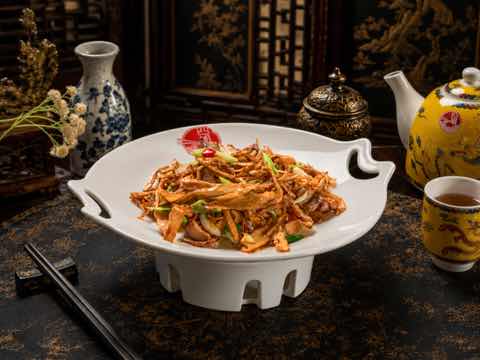 Shredded mushrooms tossed with chili in a white lotus-shaped dish