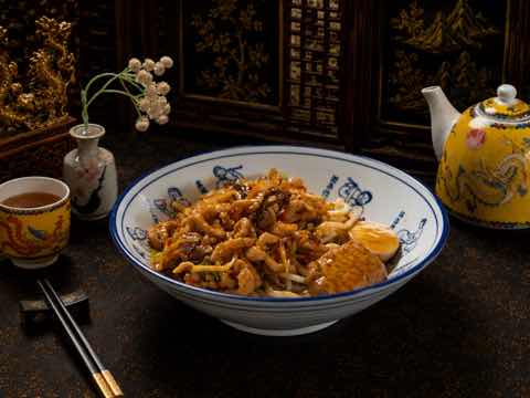 Noodle bowl heaped with crisp shredded pork