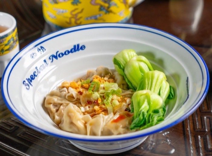 A Special Noodle bowl of wontons in clear broth with greens