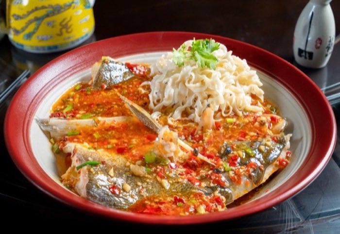 Steamed fish finished with chopped red chili and spring onion
