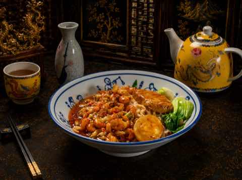 Noodles topped with sweet chili chicken, greens and a soft egg