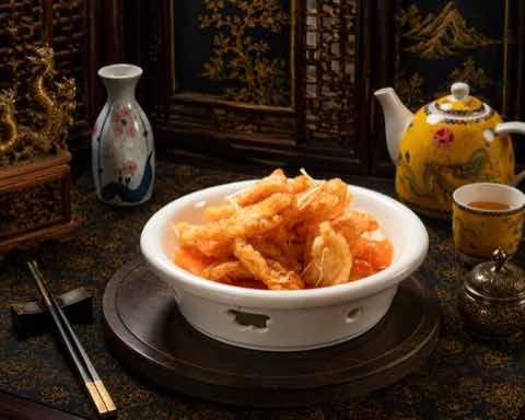 Crisp battered pork in a sweet and sour glaze in a white bowl