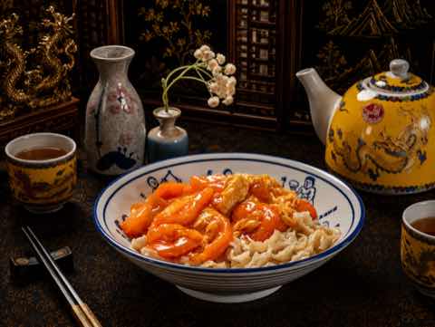 Noodles topped with prawns in a sweet and sour glaze